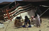Bedouin women and children sitting on sand outside tentFemale Woman Girl Lady Kids Middle East Qatari