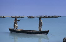 Fishermen in a wooden canoe with fishing boats at anchor beyondMiddle East Qatari