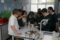 Food technology science pupils carrying out an experiment to measure the evaporation of a salt solution using a bunsen burner.European Immature Kids Learning Lessons Teaching