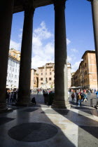 Piazza della Rotonda seen through the granite columns of the Pantheon with tourists walking in the squareEuropean Italia Italian Roma Southern Europe History Holidaymakers Religion Religious Tourism