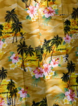 Bright Yellow shirt with a pattern of coconut palm trees  flowers and the word Caribbean displayed for sale in CliftonBeaches Resort Sand Sandy Scenic Seaside Shore Tourism West Indies Windward Islan...