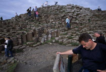 Visitors walking over the interlocking basalt stone columns left by volcanic eruptions.European Eire Holidaymakers Scenic Tourism Tourist Ireland Irish Northern Europe Poblacht na hireann Republic...
