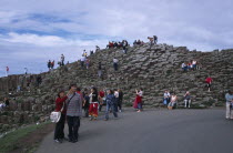 Visitors walking over the interlocking basalt stone columns left by volcanic eruptions.European Eire Holidaymakers Scenic Tourism Tourist Ireland Irish Northern Europe Poblacht na hireann Republic...