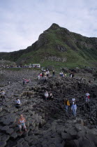Visitors walking over the interlocking basalt stone columns left by volcanic eruptions.European Eire Holidaymakers Scenic Tourism Tourist Ireland Irish Northern Europe Poblacht na hireann Republic...