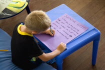 Young left handed boy at Christmas Eve sitting down and writing his Santa List at a tableCultural Cultures Immature Kids Order Fellowship Guild Club Religious West Indies Xmas Christmas Religion Youn...