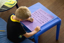 Young left handed boy at Christmas Eve sitting down and writing his Santa List at a tableCultural Cultures Immature Kids Order Fellowship Guild Club Religious West Indies Xmas Christmas Religion Young Unripe Unripened Green One individual Solo Lone Solitary