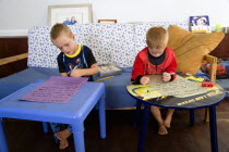 Two young left handed boys on Christmas Eve sitting down on a sofa and writing their Santa Lists at tablesCultural Cultures Immature Kids Order Fellowship Guild Club Religious West Indies Xmas Christ...