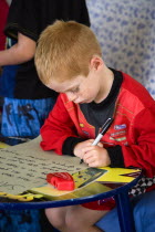 Young left handed boy at Christmas Eve sitting down and writing his Santa List at a tableCultural Cultures Immature Kids Order Fellowship Guild Club Religious West Indies Xmas Christmas Religion Youn...