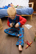 Young red headed boy in his pyjamas playing on the floor with his presents on Christmas DayCultural Cultures Immature Kids Order Fellowship Guild Club Religious West Indies Xmas Christmas Religion Yo...