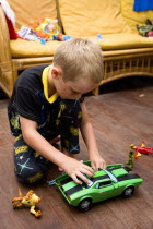 Young boy in his pyjamas playing on the floor with his green toy car and other presents on Christmas DayCultural Cultures Immature Kids Order Fellowship Guild Club Religious West Indies Xmas Christma...