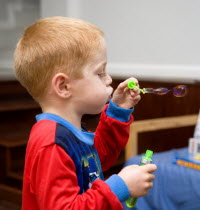 Young red headed boy in his pyjamas blowing soapy bubbles indoorsCultural Cultures Immature Kids Order Fellowship Guild Club Religious West Indies Xmas Christmas Religion Young Unripe Unripened Green...