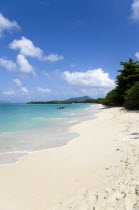 The calm clear blue water breaking on Paradise Beach in LEsterre Bay as two men beach their boatCaribbean Grenadian Greneda West Indies Grenada 2 Beaches Male Man Guy Resort Sand Sandy Scenic Seaside...