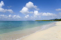 The calm clear blue water breaking on Paradise Beach in LEsterre Bay with Sandy Island  Petite Martinique and High North mountain in the distance and people walking along the sandy shorelineCaribbean...