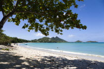 The calm clear blue water breaking on Paradise Beach in LEsterre Bay with Cistern Point and the Sisiter Rocks in the distance. A small number of people on the beach and in the waterCaribbean Grenadia...
