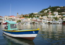 Fishing boat moored in the Carenage harbour of the capital city of St Georges with houses and the roofless cathedral damaged in Hurricane Ivan on the nearby hillCaribbean Grenadian Greneda West Indie...