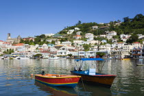 Water taxi boats moored in the Carenage harbour of the capital city of St Georges with houses and the roofless cathedral damaged in Hurricane Ivan on the nearby hillCaribbean Grenadian Greneda West I...