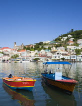 Water taxi boats moored in the Carenage harbour of the capital city of St Georges with houses and the roofless cathedral damaged in Hurricane Ivan on the nearby hillCaribbean Grenadian Greneda West I...