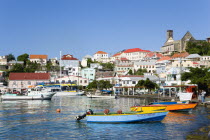 Water taxi boats moored in the Carenage harbour of the capital city of St Georges with houses and the roofless cathedral damaged in Hurricane Ivan on the nearby hillCaribbean Grenadian Greneda West I...