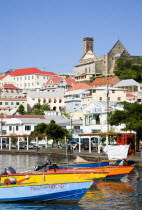 Water taxi boats moored in the Carenage harbour of the capital city of St Georges with houses and the roofless cathedral damaged in Hurrican Ivan on the nearby hillCaribbean Grenadian Greneda West In...