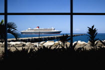 The Queen Mary 2 liner at anchor beyond a jetty off the capital city of St Georges seen through the window of the cruise ship terminalCaribbean Grenadian Greneda West Indies Grenada Two