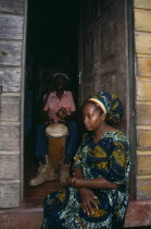 Rastafarian couple with man playing bongo drums inside home while woman sits in open doorway.Percussion InstrumentDrumsFemale Women Girl Lady Jamaican Male Men Guy West Indies Female Woman Girl La...