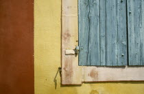 Detail of a turquoise window shutter on a yellow and red wallFrench Western Europe European