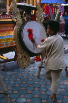 THAILAND, North, Chiang Mai, Southeast Asia Wat Chettawan Buddhist temple on Tha Phae Road with Young boy playing drum suspended on frame with red and gold dragon carvings.