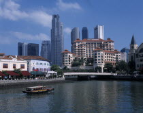 Boat on the Singapore River overlooked by hotel and high rise buildings.Asian Singaporean Singapura Southeast Asia Southern Xinjiapo