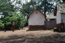 Traditional thatched house with intricate patterns on walls. Man and woman walking past.African Asante Classic Classical Ghanaian Historical History Older Western Africa 1 Single unitary Female Women...