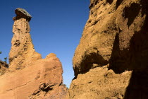 Colorado Provencal.  Cheminee de Fee or Fairy Chimneys.  Capped  eroded ochre rock pinnacle seen from park trail against cloudless blue sky.Ochre Trail European French Western Europe