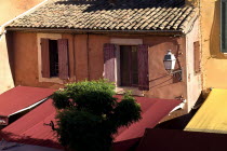 Roussillon.  Provencal colours in the town centre  exterior facade of building with tiled roof  red awning and pale ochre and orange walls.European French Western Europe Center