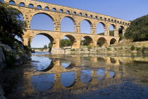 Pont du Gard.  View from west side of the Roman aqueduct in glowing evening light with reflection in the water below.Bridge arch European French Western Europe Warm Light