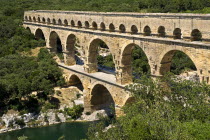Pont du Gard Roman aqueduct from a high vantage point on the western side showing three tiers of continuous arches spanning river and visitors on bridge.arch stone European French Western Europe