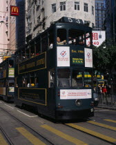 Hong kong Island tram on city street with high rise buildings and advertising hoardings.  Asia Asian Chinese Chungkuo Jhonggu Zhonggu