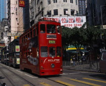 Hong kong Island trams on city street with high rise buildings and advertising hoardings and McDonalds sign overhead.  Asia Asian Chinese Chungkuo Jhonggu Zhonggu