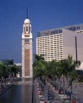 Kowloon Star ferry clock tower at end of rectangular pool lined by palms and flowerbeds.Asia Asian Chinese Chungkuo Jhonggu Zhonggu