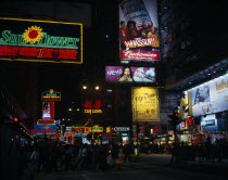 Illuminated advertising hoarding and neon signs on Nathan Road at night with crowds crossing road at traffic lights in foreground. multi-coloured colourful Asia Asian Chinese Chungkuo Colorful Jhongg...