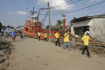 Tsunami. Volunteers and the locals walk past a fishing boat ploughed into a house. The damage caused by the tsunami  nothing is left standing in the village  about 125kms north of Phuket on the 31st D...