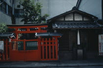 Exterior of house beside red painted Torii style gateway.Asia Asian Japanese Nihon Nippon