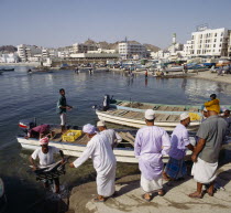 Fish Souk with locals unloading a catch at jetty. Boats and the waterfront in the background.Market Middle East Omani
