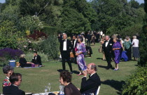 Opera attendees enjoying picnics in the gardens during performance intervalEuropean Great Britain Northern Europe Public Presentation UK United Kingdom British Isles