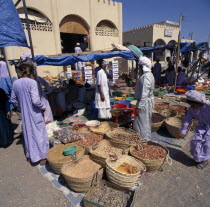Souk with local people around stalls with spices displayed on ground in baskets Market Middle East Omani