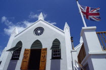 St Peters Church facade with open door and windows. British Union Jack flag flying outside.Bermudian Religious West Indies Religion