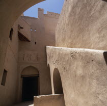 Fort. Interior view of plain walls  doorway with arch and  blue sky above Hajr Middle East Omani Hajar