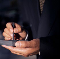 Detail of businessman s hands using PDA palm held personal organiser.BusinessTechnology American North America Northern One individual Solo Lone Solitary United States of America