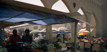 Mutrah produce market.  Covered stalls beside arched entrance with displays of fruit and vegetables.Middle East Omani