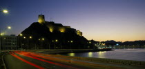 Mutrah Fort  built by the Portuguese in the 1580s  situated above town.  Illuminated at night with light trails from traffic on the road below lined by street lights.History Middle East Nite Omani Po...