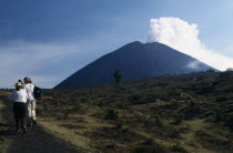 Smoking cone of volcano with people walking a dirt path in the foreground.American Central America Hispanic Latin America Latino Scenic Southern
