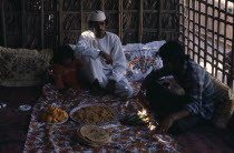 Two men and girl sitting with a meal served in communal dishes in front of them.2 Kids Male Man Guy Middle East Omani Male Men Guy