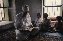 Children studying the Koran with Islamic teacherKids Learning Lessons Middle East Old Senior Aged Omani Quran Religion Religious Teaching